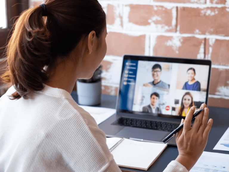 Uma mulher de costas para a tela fazendo uma videoconferencia com clientes